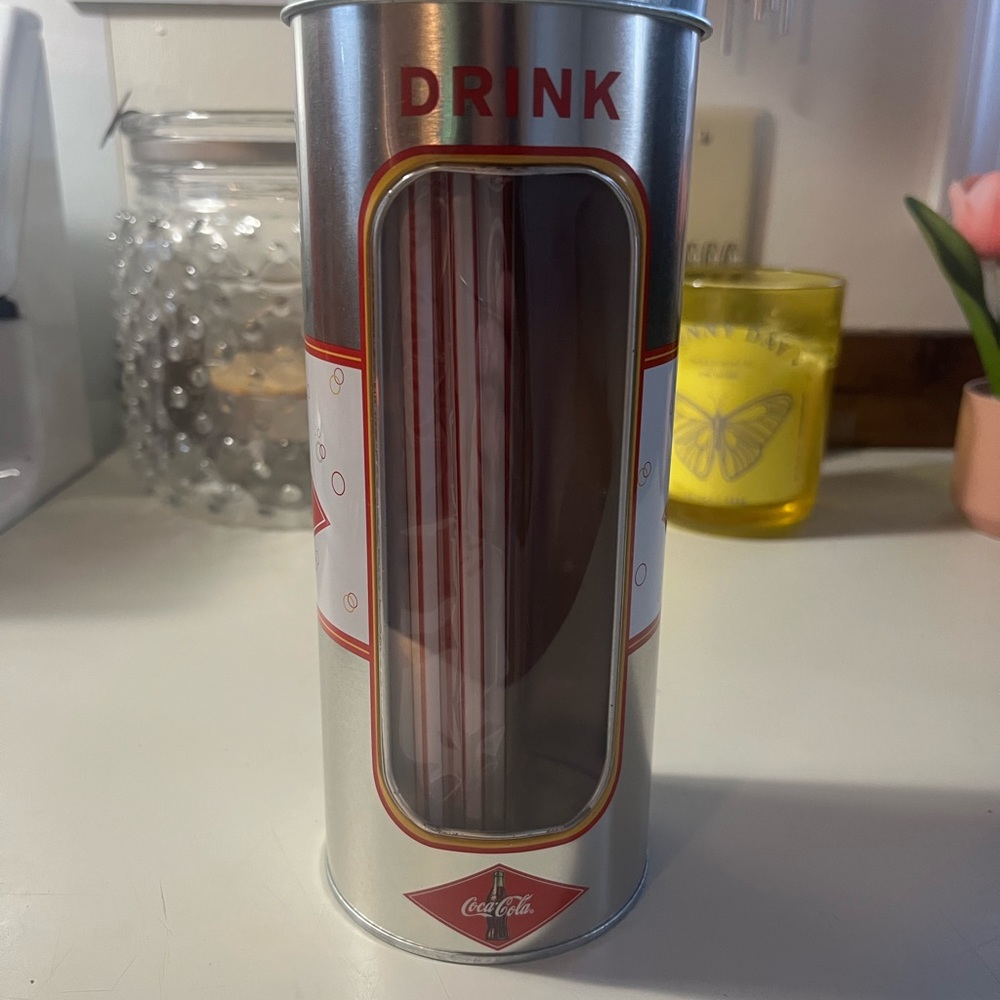 Vintage coco-cola canister with straws.